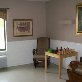 A cozy corner with a chess set on the table beside a comfortable chair and wall art.
