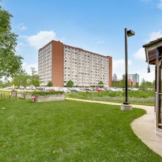 A view of a residential apartment building surrounded by green grass and trees in an urban setting.