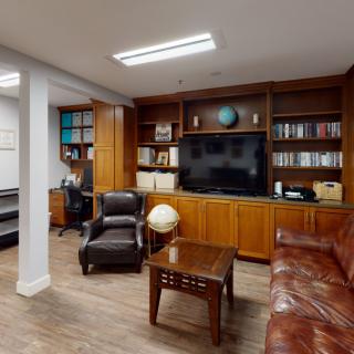 A cozy library office with a leather sofa, armchair, bookshelves, and a globe.