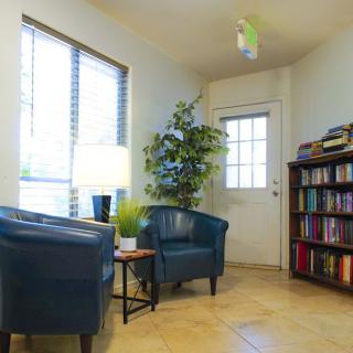 Cozy living room with chairs, a bookshelf, and natural light.