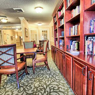 A cozy library setting with wooden bookshelves and a table surrounded by chairs.