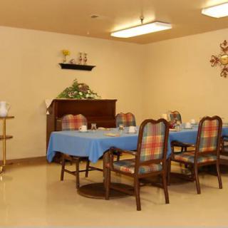 A cozy dining room with a table and chairs, featuring blue tablecloths and plaid upholstery.