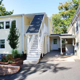 A two-story residential house with exterior stairs and a driveway.