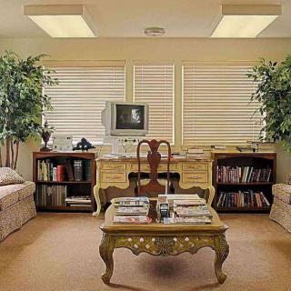 A vintage-themed office with a classic desk, old computer, and cozy seating area.