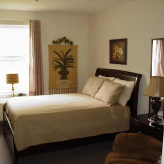 A cozy and inviting bedroom featuring a neatly made bed, decorative artwork, and warm lighting.