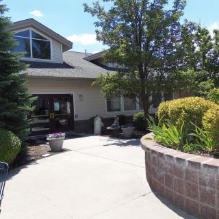 A building with a landscaped entrance, featuring greenery and trees.