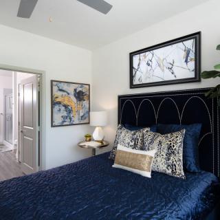 A stylish bedroom featuring a navy blue bedspread, decorative pillows, and contemporary artwork.