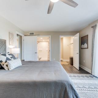 A modern and minimalist bedroom featuring a large bed, stylish decor, and a ceiling fan.