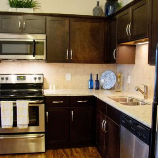 A modern kitchen with dark wood cabinets and stainless steel appliances.