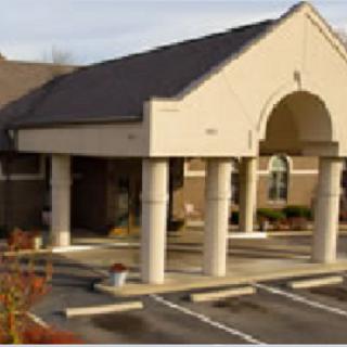 A modern building entrance with distinct architectural features and a spacious parking lot.