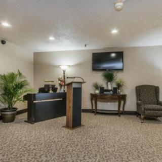 A serene funeral home interior with a podium, seating area, and decorative plants.