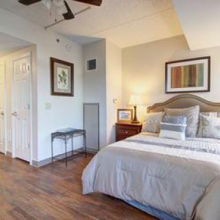 A cozy bedroom with a wooden floor, featuring a neatly made bed and stylish decor.