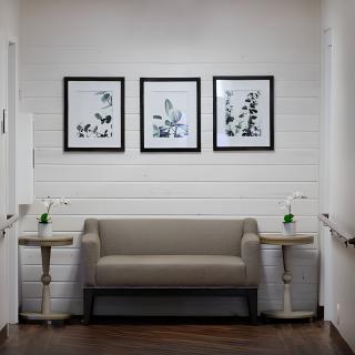 A neatly arranged waiting area with a sofa, side tables, and framed wall art.