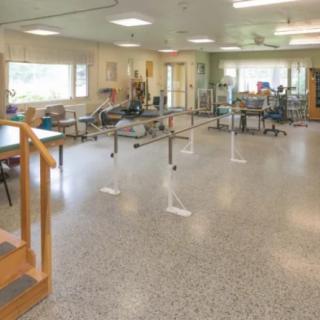 A spacious physical therapy room equipped with parallel bars and other rehabilitation equipment.