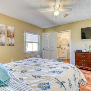 A cozy bedroom with a bed, dresser, and TV, featuring a ceiling fan and decorative wall art.