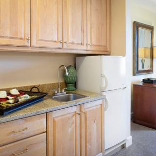 A kitchenette with wooden cabinets, a small sink, and a white refrigerator.