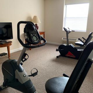 A home exercise room featuring stationary bikes and a television.
