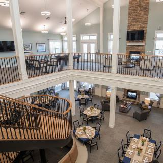 A spacious two-story interior with a dining and lounge area, featuring a central staircase and open floor plan.