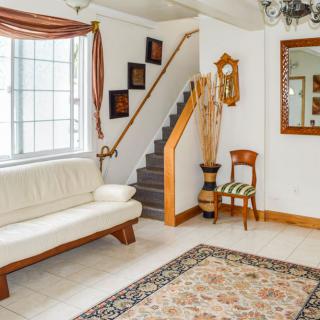 A cozy living room with a white sofa, a staircase, and elegant decor.