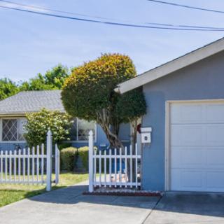 A suburban house with a white picket fence and garage.