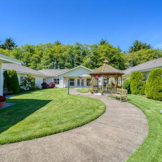 A charming house with a well-maintained garden, featuring a central gazebo and a curving pathway surrounded by lush greenery.