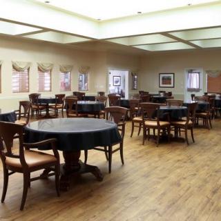 An empty dining room with multiple tables and chairs on a wooden floor.