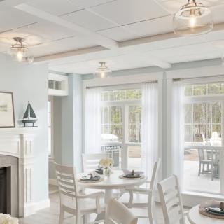 A bright and modern living and dining area with white furnishings and large windows.