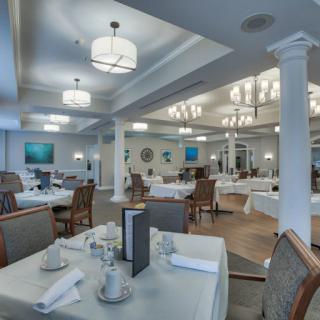 An elegant restaurant dining room with neatly arranged tables and chairs, featuring sophisticated lighting and decor.