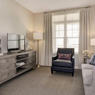 A cozy living room with neutral tones, featuring a sofa, armchair, and elegant decor.