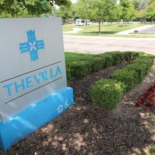 A decorative sign for 'The Villa' surrounded by landscaped gardens.