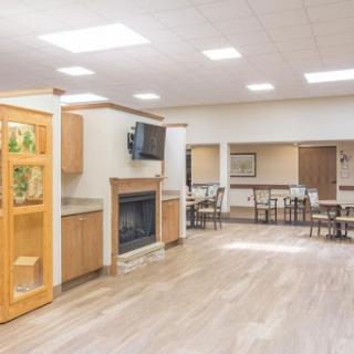 A spacious and inviting common area featuring a fireplace, dining tables, and natural light.