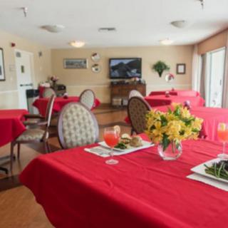 A cozy dining room with tables covered in red tablecloths, set with meals and floral centerpieces.