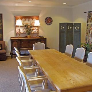 A conference room with a large wooden table and chairs, featuring decorative elements and a cabinet.