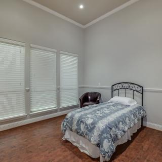 A minimalist bedroom with a single bed, chair, and large windows.