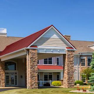 A residential-style building with a red roof and stone facade, featuring a welcoming entrance and well-maintained landscaping.