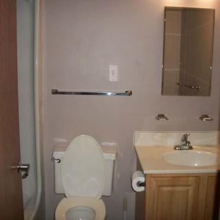 A small bathroom featuring a toilet, sink, and mirror.