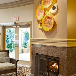 A cozy lobby area with a fireplace, artistic wall decor, and comfortable seating.