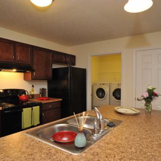 A modern kitchen with an adjoining laundry room, featuring a spacious countertop and appliances.