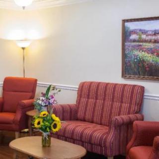 A cozy living room with red furniture, a lamp, and a painting on the wall.