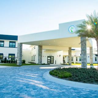 A modern building entrance with a covered driveway and landscaped surroundings.
