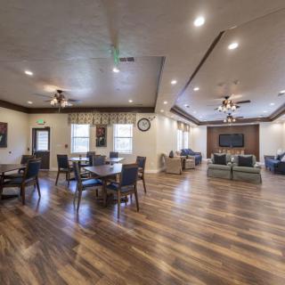 A spacious interior living room with tables, chairs, and a wooden floor.