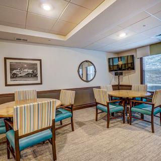 A modern dining area with tables, chairs, and a wall-mounted TV.