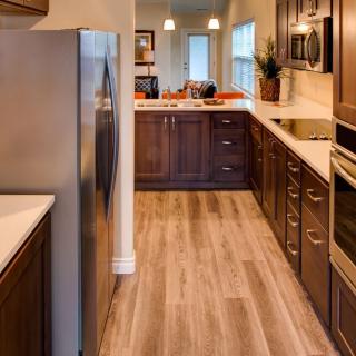 A modern kitchen with wooden cabinets, stainless steel appliances, and a hardwood floor.