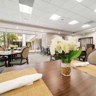 A bright and elegant restaurant dining area with neatly arranged tables, adorned with floral centerpieces.