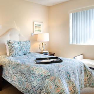 A cozy bedroom with a single bed, bedside table, and a window.