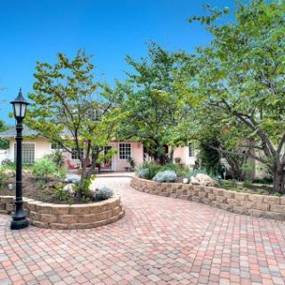 A beautifully landscaped front yard featuring a winding brick pathway and lush greenery.