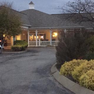 A warmly lit building entrance with surrounding landscaping in the evening.