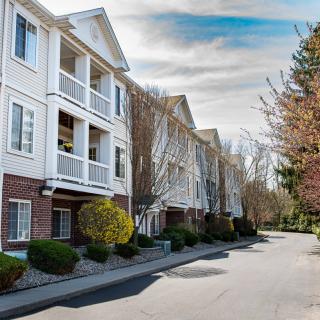 A view of a residential apartment building with white exteriors and surrounding trees.