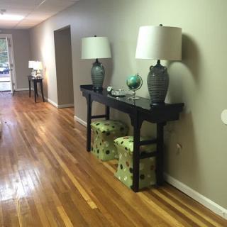 A modern hallway with wooden flooring, featuring a console table adorned with lamps and decorative accents.