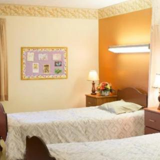 A cozy bedroom featuring two neatly made single beds, a warm lamp, and decorative touches like a flower arrangement and picture frame on the wall.